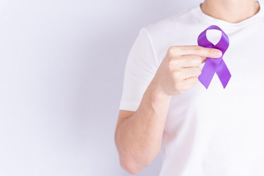 World cancer day, hands holding purple ribbon on grey background with copy space for text. Healthcare and medical concept.