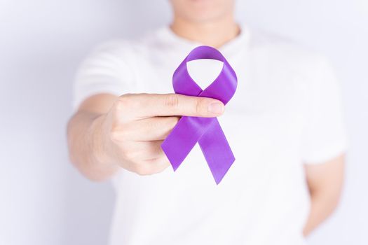 World cancer day, hands holding purple ribbon on grey background. Healthcare and medical concept.