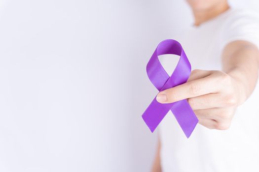 World cancer day, hands holding purple ribbon on grey background with copy space for text. Healthcare and medical concept.