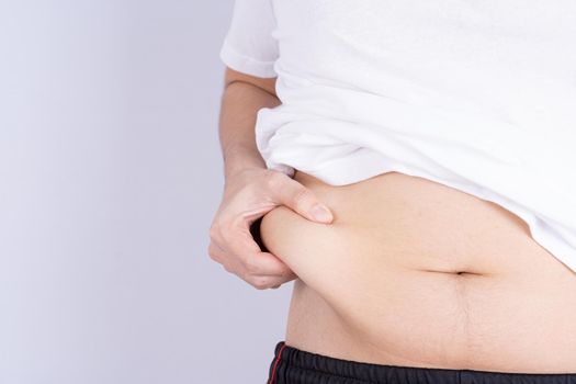 Fat man holding excessive fat belly, overweight fatty belly isolated grey background. Diet lifestyle, weight loss, stomach muscle, healthy concept.