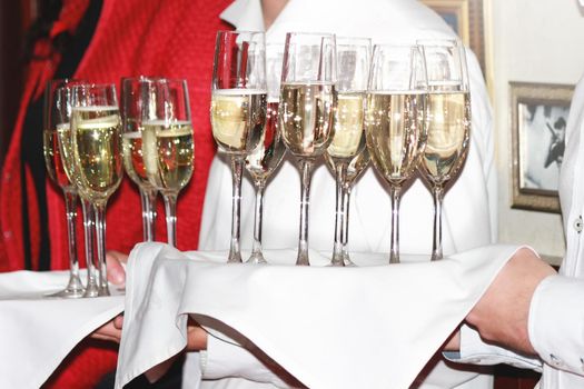 a waiter hands champagne glasses to guests at a corporate party. drinks