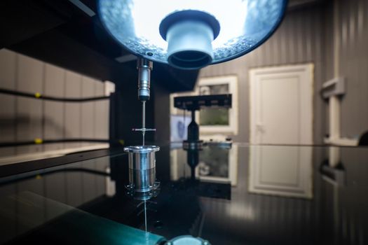 CMM - Coordinate Measuring Machine - contact probe measure aluminium sample part on glass table surface. High precision production metrological control process. Led lamp lighting.