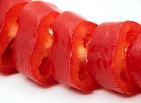 Capi of ripe juicy sweet pepper cut into rings on a white plate.