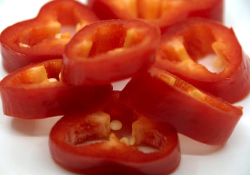 Capi of ripe juicy sweet pepper cut into rings on a white plate.