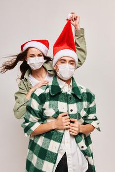 A man in a plaid shirt and a happy woman in a medical mask with a festive hat on her head. High quality photo