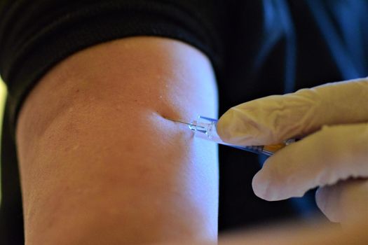 close-up of a hand holding an injection before injecting into the arm