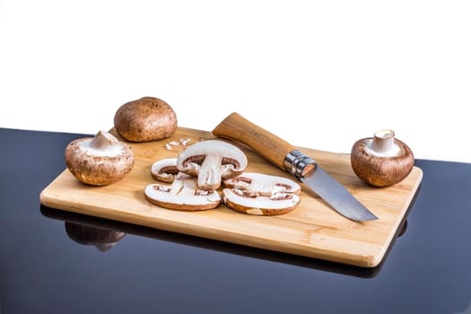 Royal champignons, Parisian champignons, mushrooms on bamboo wooden chopping board. Dark wooden background. Side view.