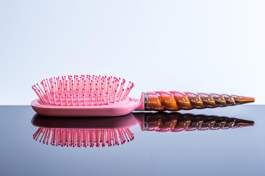 Beautiful pink hairbrush on a black glossy surface. Women's Hair Care Accessories. Side view