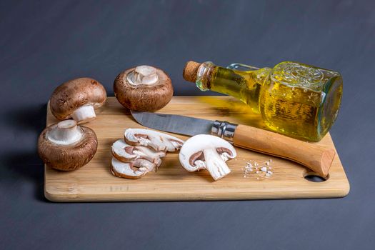 Still life of mushrooms, Royal champignons on a cutting board with knife and a bottle with olive oil, high angle view