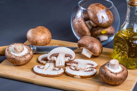 Royal champignons, Parisian champignons, mushrooms on bamboo wooden chopping board. Dark wooden background. Side view.