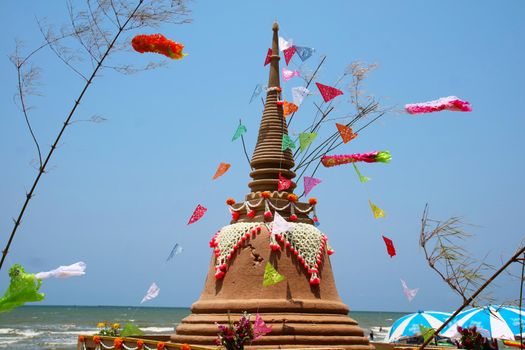 Giant sand pagoda and flags in Songkran festival represents In order to take the sand scraps attached to the feet from the temple to return the temple in the shape of a sand pagoda