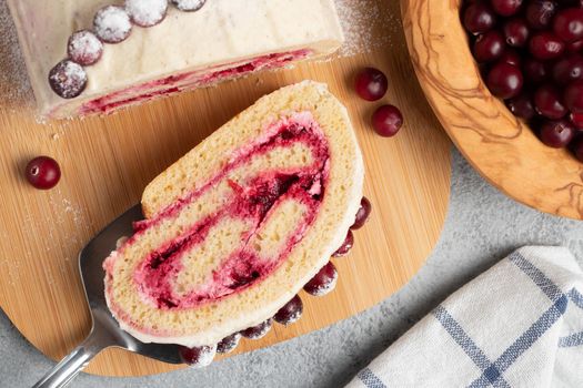 Homemade biscuit sweet roll with cranberries and cream on gray table, top view, flat lay.