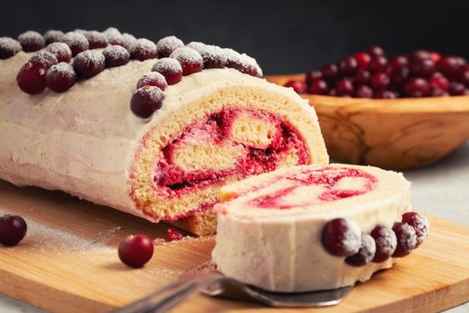 Homemade biscuit sweet roll with cranberries and cream on gray table.