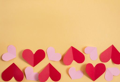 Valentine's Day background. Pink and red hearts on a pastel yellow background. Valentine's Day concept. Flat lay, top view, copy space