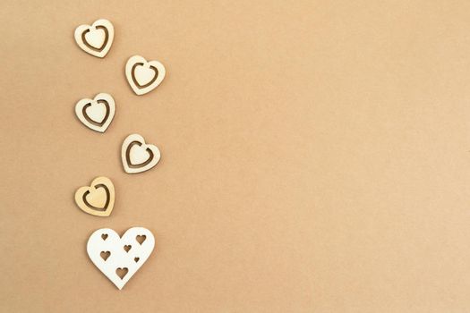 Wooden hearts on a pastel craft paper background. Abstract background with wood cut shapes. Sainte Valentine, mother's day, birthday greeting cards, invitations. Copy space.