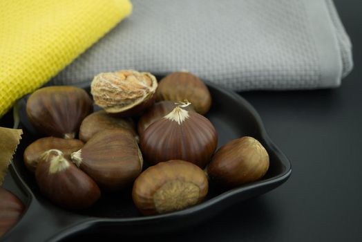 Fresh chestnuts also called sweet chestnut, Castanea sativa, Spanish chestnut in a black pan, low angle view and shallow focus