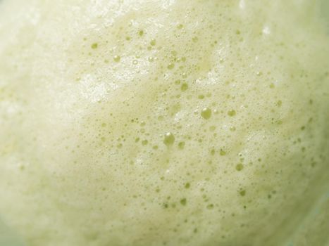 Green foam texture extreme close up as background. Perfect green matcha tea latte foam with bubbles macro shoot. Copy space for text.
