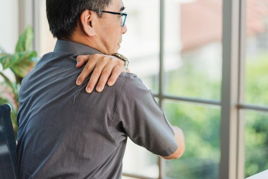 Asian hard senior businessman working with laptop computer has a problem with shoulder pain. Old man feeling pain after sitting at desk long time, Healthcare and medicine office syndrome concept