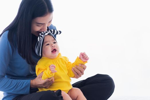 Portrait of beautiful young Asian mother playing and smiling together with his newborn little baby at home, Parent mom and little kid relaxing in the bedroom, Family having fun together