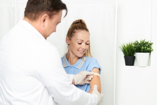 male doctor in a white coat seals his hand with adhesive plaster. High quality photo