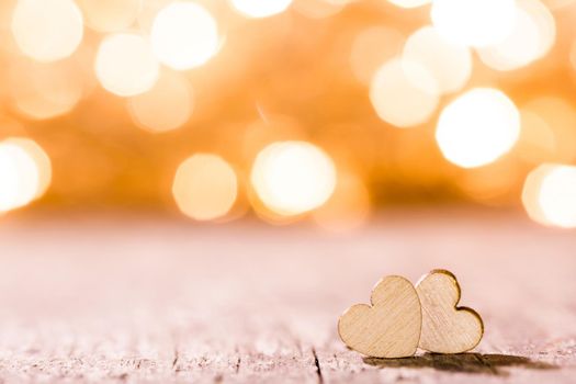 Two handmade wooden hearts on beautiful golden bokeh background. Vintage style. Love Valentine's Day concept.