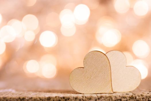 Two handmade wooden hearts on beautiful golden bokeh background. Vintage style. Love Valentine's Day concept.