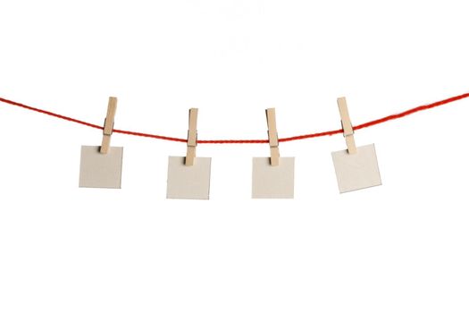 Set of four white blank paper notes held on red string with clothespins isolated on white background