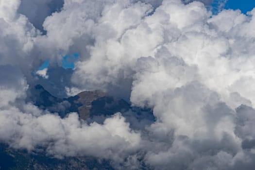 White fluffy clouds on the tops of mountains.