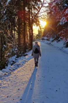 Woman hiking on snow in white winter forest berore the sunset. Recreation and healthy lifestyle outdoors in nature.