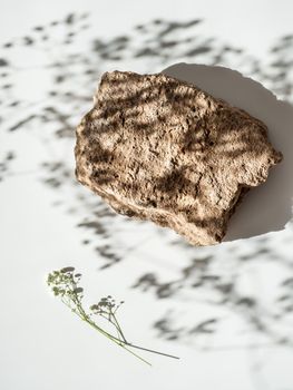 Mockup geometric shape podium top view. Stone shape with gypsophila flowers shades over white background. Vertical. Flat lay. Can use as perfume and cosmetic mock up