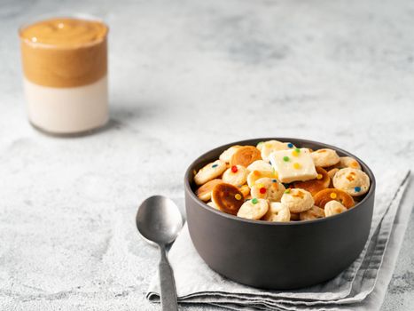 Mini pancakes cereal and dalgona coffee on gray cement background, copy space. Trendy food and drink - tiny panckakes served sprinkles and whipped instant coffee with milk or korean dalgona coffee