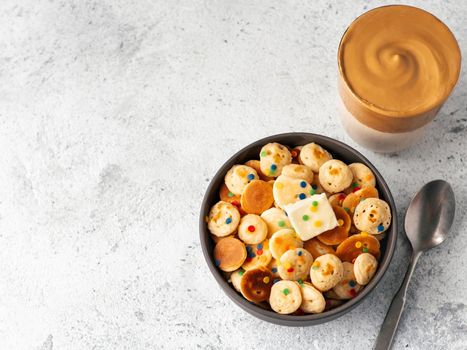 Mini pancakes cereal and dalgona coffee on gray cement background copy space. Trendy food and drink - tiny panckakes and whipped instant coffee with milk or korean dalgona coffee. Top view or flat lay