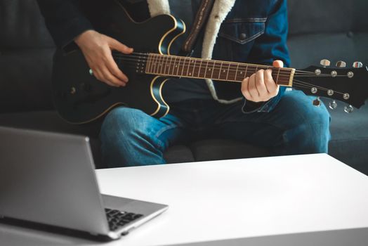 Teacher shows how to play the guitar. Remote online lesson.