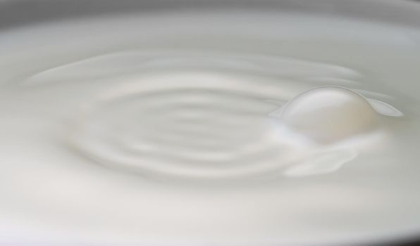 Milk drop falls into the filled cup.