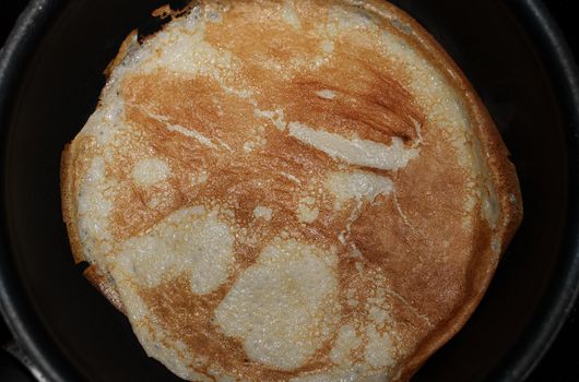 Pancake on frying pan. Making of pancakes.
