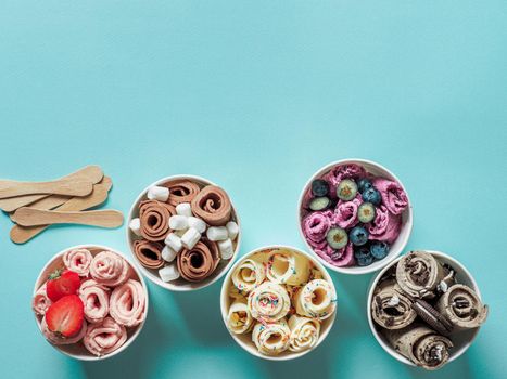rolled ice creams in cone cups on blue background. Different iced rolls top view or flat lay. Thai style rolled ice cream with copy space for text or design
