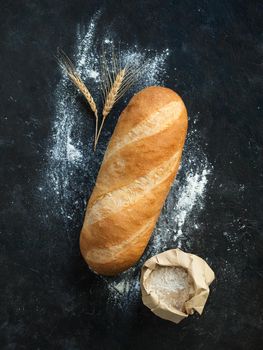 British White Bloomer or European Baton loaf bread on black background. Top view or flat lay. Copy space for text or design. Vertical.