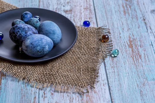 Blue Easter eggs on a dark ceramic plate on burlap on an light wooden background.Concept, healthy food, spring religious holidays.