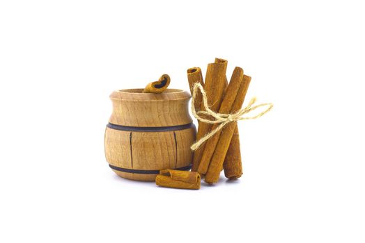 Cinnamon sticks bundle tied with jute string and a small wooden pot isolated on white background