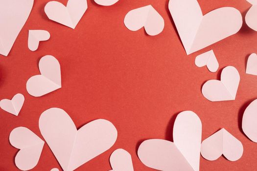 Valentine's day background. Pink hearts laid out in the form of a frame on a pastel red background. Valentine's day concept. Layout for postcards and congratulations. Flat lay, top view, copy space