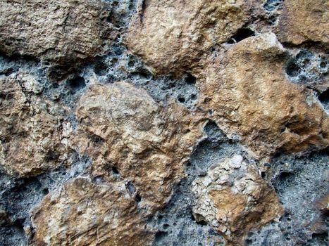 Black and rough rough texture of the stone with depressions and pits on the surface.Texture or background