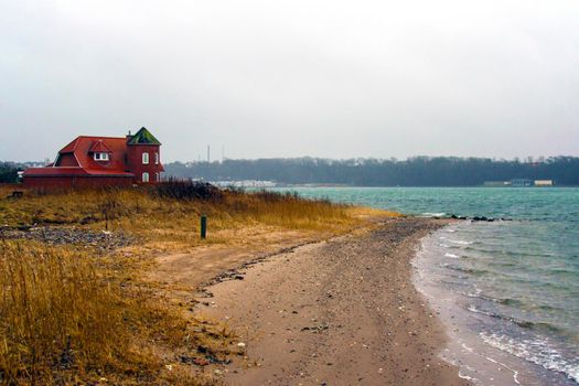 Scenic view of a small beach and red bricks house with tower on the coast of Lemvig, Denmark