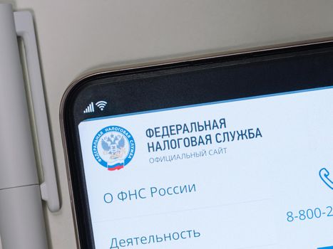 Moscow, Russia - January 25, 2021: Site of Federal Tax Service of Russia on smartphone screen over white table, near pen
