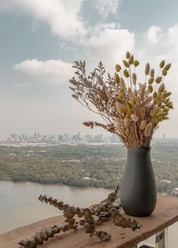 Dried flowers in ceramic vases handmade on a wooden desk on the balcony with river view background. Home decor. Space for text. Selective focus.