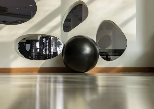 Bangkok, Thailand - 24 Jan 2021 : Black fitness exercise ball on the floor gym studio. Equipment for doing sport exercises with free space. Gym concept, Selective focus.