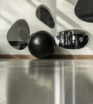 Bangkok, Thailand - 24 Jan 2021 : Black fitness exercise ball on the floor gym studio. Equipment for doing sport exercises with free space. Gym concept, Selective focus.
