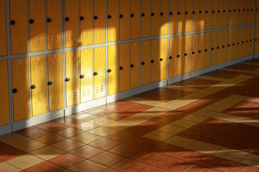 Sun shines on empty elementary school hall, numbered lockers at the wall.