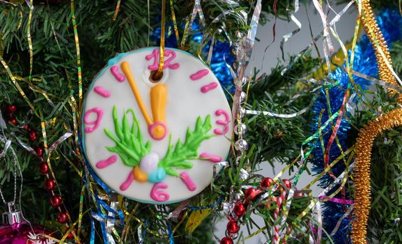 Close-up of a Christmas tree with ornaments of baubles, snowflakes, tinsel, garlands and a large gingerbread-clock.