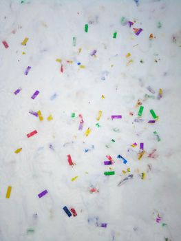 Colorful confetti glitter on the snow after holiday. No plastic, eco living concept.