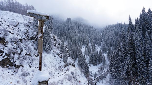 An old abandoned gazebo with views of the snowy mountains and forest. Clouds float beautifully, fir trees are covered with snow. High white hills. The stone pillars of the building are destroyed.